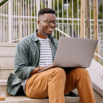 BankingForBegginers_Square.jpg Happy man with headphones working on laptop