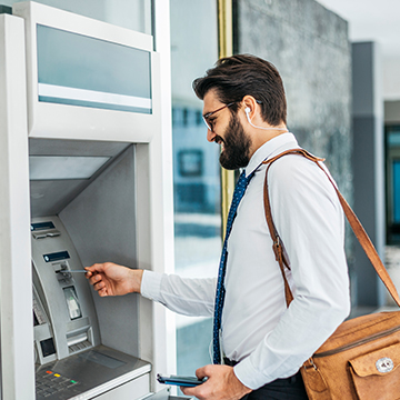 DebitCardFraud-2.jpg Man in business clothes retrieving money from ATM