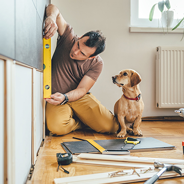 HomeEquity-Square.jpg Man measuring wall in house next to curious dog